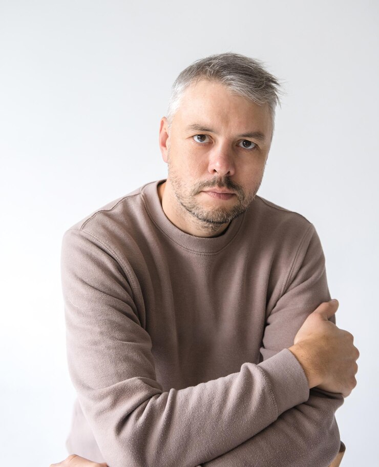 Portret van een serieuze man van middelbare leeftijd met gekruiste armen Hij draagt een taupe sweatshirt tegen