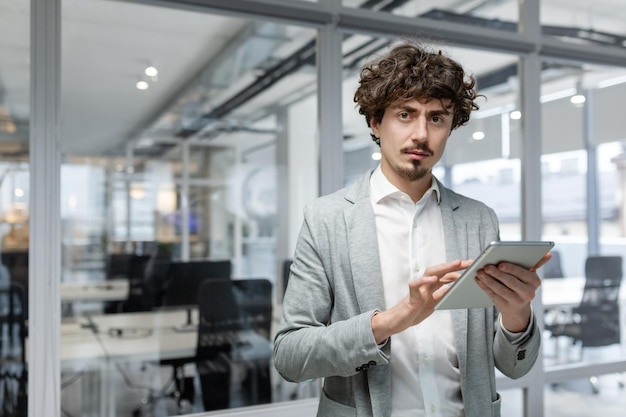 Portret van een serieuze volwassen zakenman denkende man met tabletcomputer in handen die naar de camera kijkt