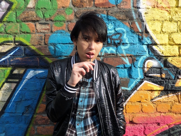 Foto portret van een serieuze vrouw tegen een graffiti muur