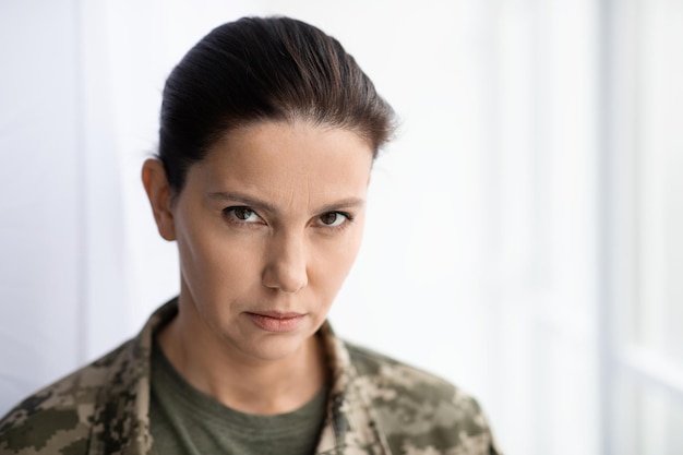 Portret van een serieuze vrouw van middelbare leeftijd in militair uniform die naar de camera kijkt