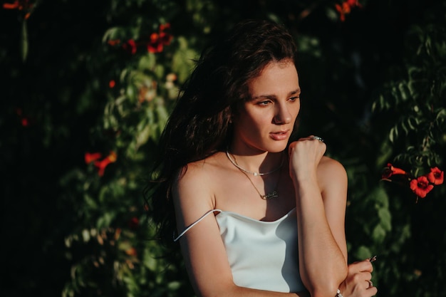 portret van een sexy blank jong meisje bij de bloeiende bomen in het park in de zomer