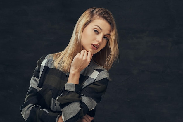 Portret van een sexy blond meisje in een fleece shirt, poseren in een studio. geïsoleerd op een donkere achtergrond.