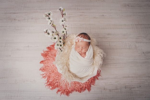 Portret van een slapende pasgeboren baby. Imitatie van een baby in de baarmoeder. bloemen als decoraties, interieur.
