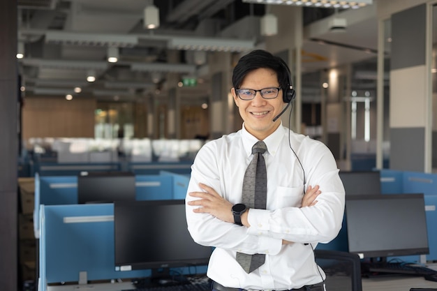 Portret van een slimme aziatische mannelijke klantenservicemedewerker met een headsetglimlach en staan in de callcenterruimte