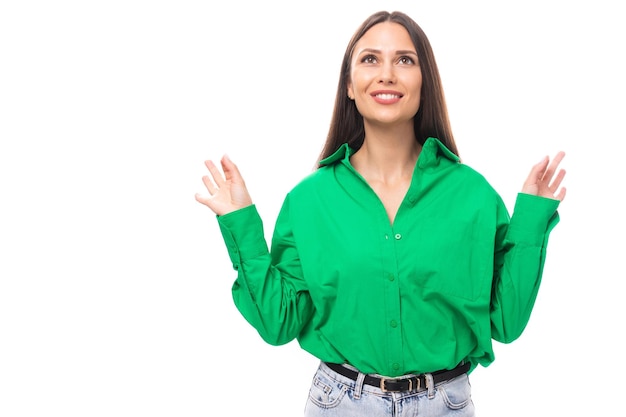 portret van een slimme bedachtzame slanke schattige bruine brunette vrouw gekleed in een groen hemd glimlachend op een witte achtergrond met kopieerruimte