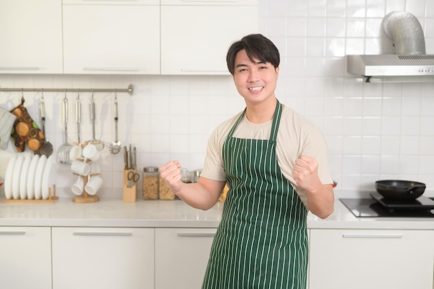 Portret van een slimme jonge Aziatische man die lacht in de keuken thuis