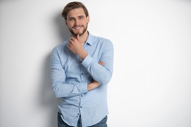 Portret van een slimme jonge man die tegen een witte achtergrond staat.