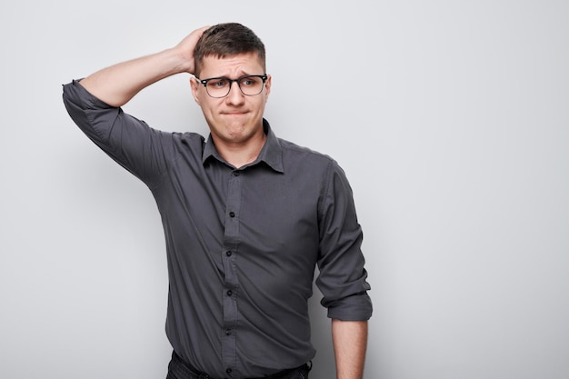 Portret van een slimme man in shirt die het hoofd aanraakt, denkt dat twijfels kiest geïsoleerd op witte studioachtergrond met kopieerruimte