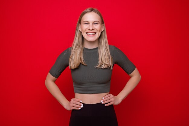 Portret van een sportieve jonge vrouw op een rode achtergrond