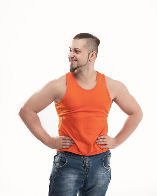 Portret van een sportieve kerelbodybuilder in jeans en oranje tshi