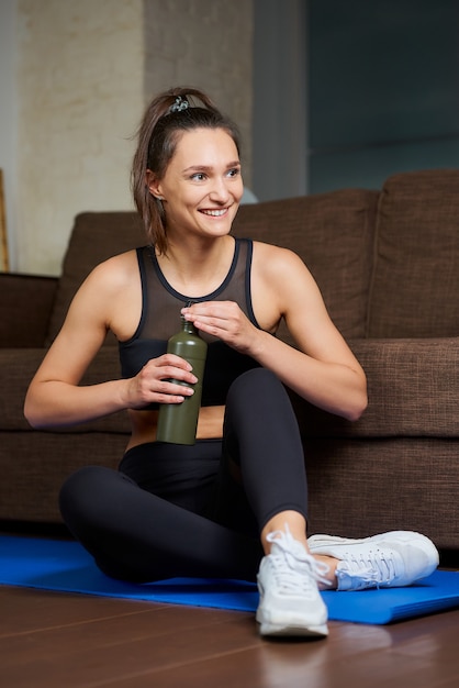 Portret van een sportieve vrouw die oefeningen thuis doet