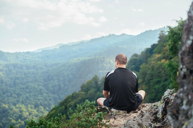 portret van een sterke atletische man die op de helling van een hoge berg zit en rust