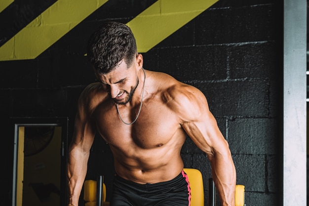 Portret van een sterke man met een naakte torso die oefeningen doet in een sportschool