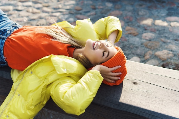 Foto portret van een stijlvol meisje met een gele puffer en een oranje gebreide muts