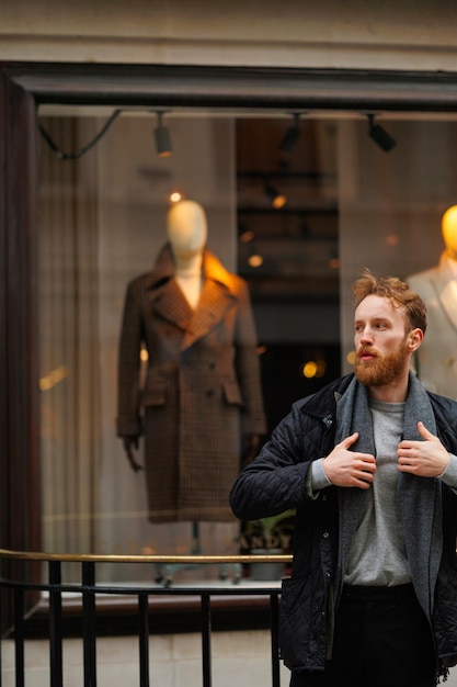 Portret van een stijlvolle bebaarde man tegen de achtergrond van een elegante kledingwinkel