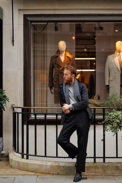 Portret van een stijlvolle bebaarde man tegen de achtergrond van een elegante kledingwinkel