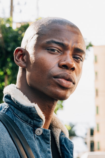 Foto portret van een stijlvolle geschoren afrikaanse jonge man kijkt naar de camera