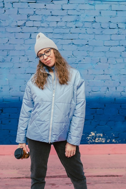 Portret van een stijlvolle vrouw in blauw jasje met koffiekopje lente buiten portret