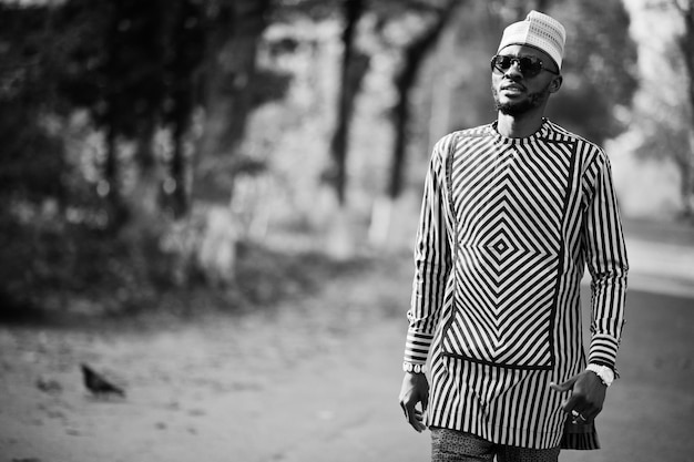 Portret van een stijlvolle zwarte Afro-Amerikaanse man met hoed en zonnebril tegen een zonnige herfstachtergrond Rijke mensen in Afrika in traditionele kleding