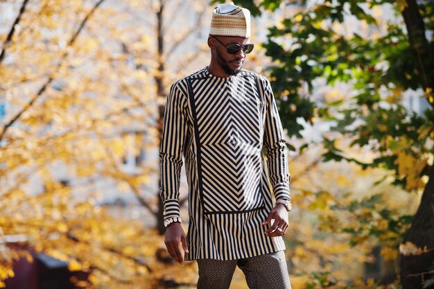 Portret van een stijlvolle zwarte Afro-Amerikaanse man met hoed en zonnebril tegen een zonnige herfstachtergrond