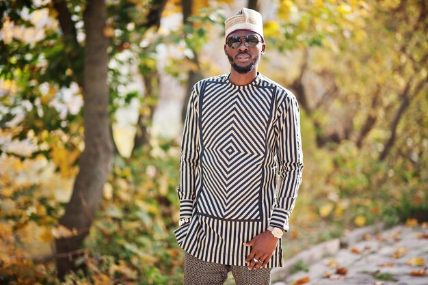 Portret van een stijlvolle zwarte Afro-Amerikaanse man met hoed en zonnebril tegen een zonnige herfstachtergrond