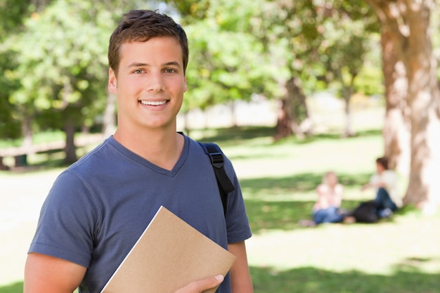 Portret van een student die terwijl het houden van een handboek glimlacht