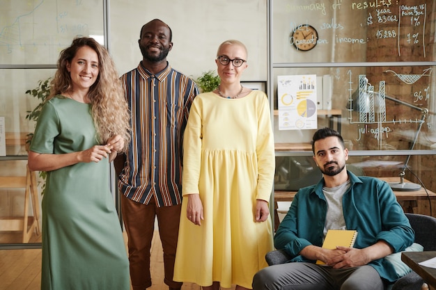 Portret van een succesvol zakelijk team van ontwerpers die naar de camera kijken terwijl ze op kantoor werken