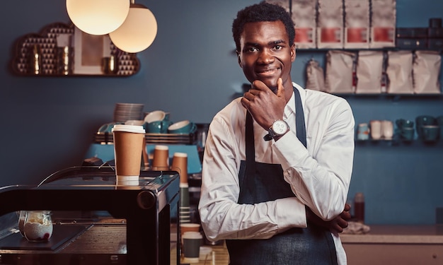Portret van een succesvolle Afro-Amerikaanse eigenaar die naar de camera glimlacht terwijl hij in de coffeeshop staat.