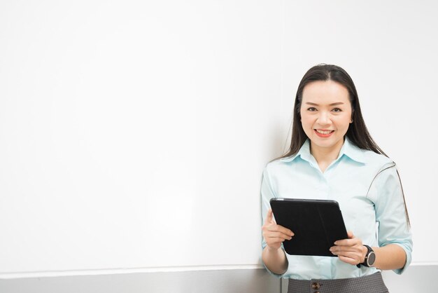 Portret van een succesvolle Aziatische zakenvrouw van middelbare leeftijd die een tablet vasthoudt die naar de camera glimlacht