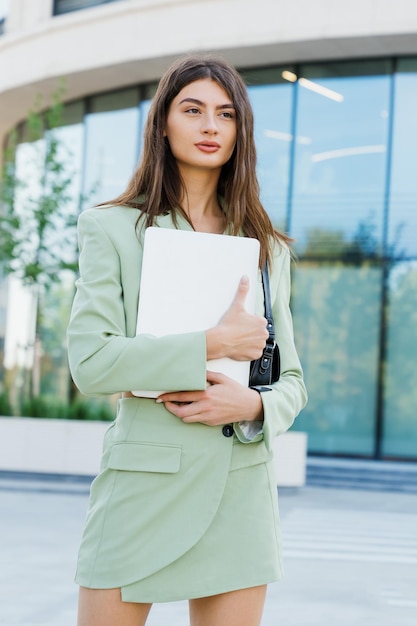 Portret van een succesvolle jonge freelance vrouw met een laptop buiten