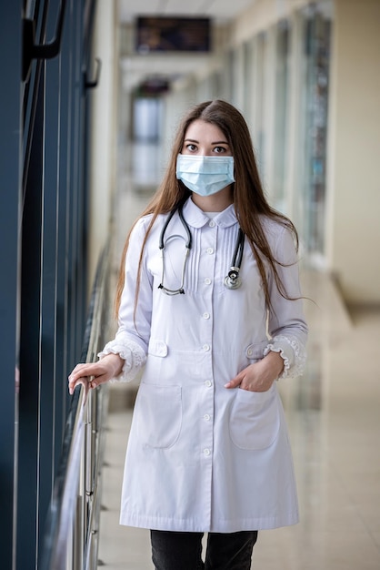 Portret van een succesvolle lachende verpleegster die een masker draagt ter bescherming tegen covid