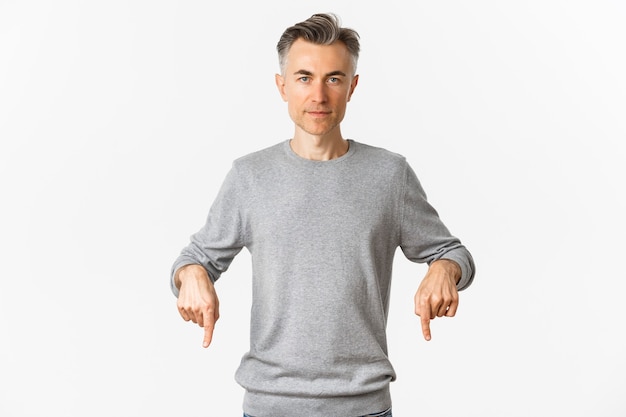 Portret van een succesvolle man van middelbare leeftijd in grijze trui, wijzende vingers