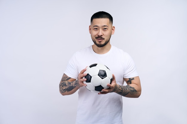 Portret van een succesvolle sportman voetbalspeler die een bal vasthoudt die naar de camera kijkt