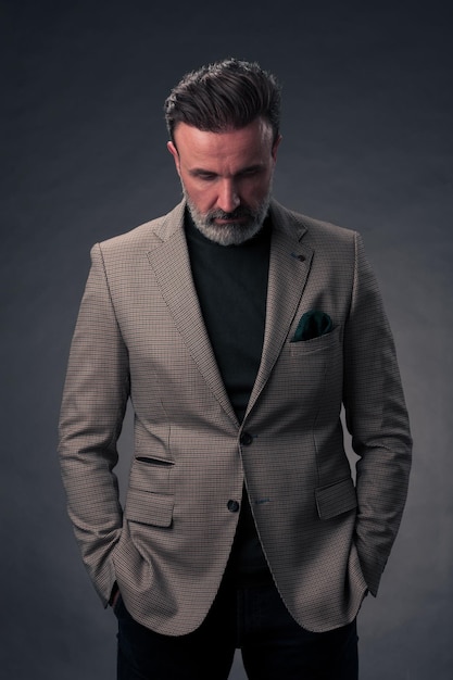 Portret van een succesvolle stijlvolle elegante senior zakenman met een grijze baard en casual zakelijke kleding vertrouwen in fotostudio geïsoleerd op donkere achtergrond gebaren met handen. Foto van hoge kwaliteit