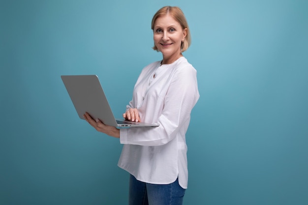 Portret van een succesvolle volwassen zakenvrouw met blond haar die op internet surft met een laptop