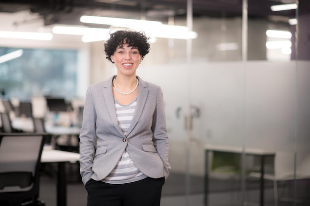 Portret van een succesvolle vrouwelijke softwareontwikkelaar met een krullend kapsel bij een modern startup-kantoor