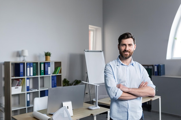 Portret van een succesvolle zakenman die lacht en werkt op een laptop in een modern, licht kantoor