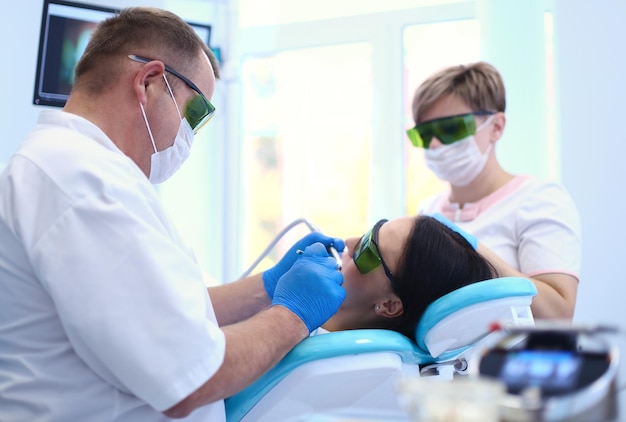 Portret van een tandarts die de tanden van een jonge vrouwelijke patiënt behandelt