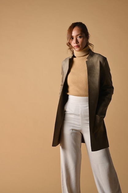 Portret van een tedere vrouw met trenchcoat die op een beige achtergrond staat Mode studio foto herfst en winter concept