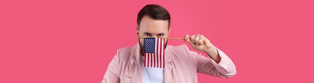 Foto portret van een tevreden jonge man met een baard met een amerikaanse vlag op een rode studioachtergrond grote amerikaanse patriot en verdediger van vrijheid