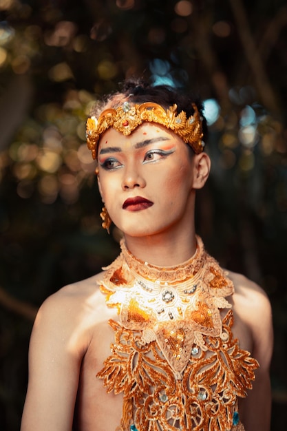 Portret van een Thaise man met een gouden ketting en een gouden kroon terwijl hij zonder shirt in de jungle zit