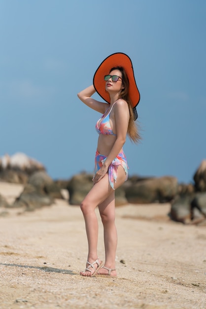 Portret van een Thaise vrouw in een bikini en een roze hoed die zich voordeed op het strand