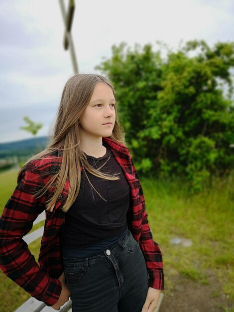 Foto portret van een tienermeisje dat tegen bomen staat