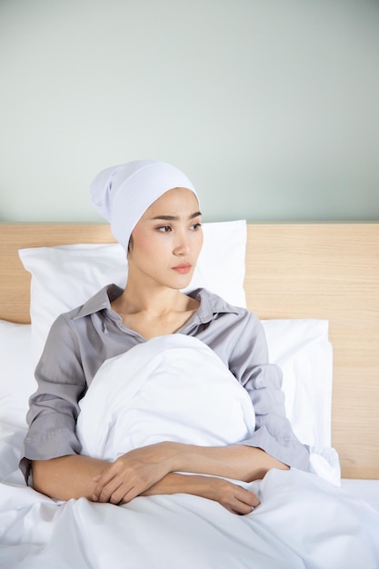 Foto portret van een trieste aziatische vrouw met kankerpatiënt die een hoofddoek draagt na ernstig haarverlies als gevolg van chemotherapie