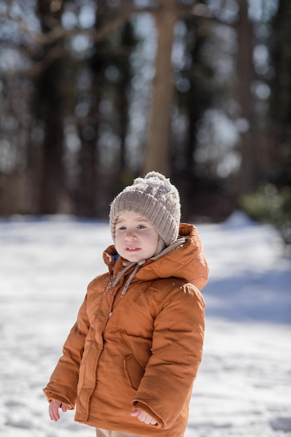 Portret van een tweejarige jongen die in de winter in de verse sneeuw staat en buiten speelt