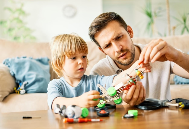 Portret van een vader en een zoon die zoon leert om thuis gereedschap en vakmanschap te gebruiken met creatief speelgoed