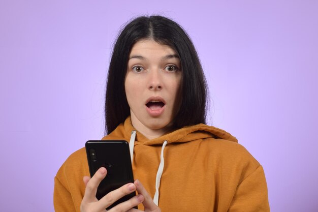 portret van een verbaasde jonge vrouw met haar smartphone in haar handen