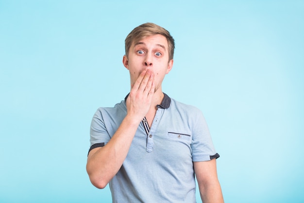 Portret van een verbaasde man die zijn mond bedekt over blauw