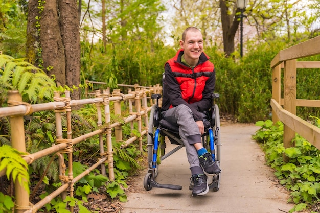 Portret van een verlamde jonge man in een openbaar park in de stad Zittend in de rolstoel slenterend over het pad