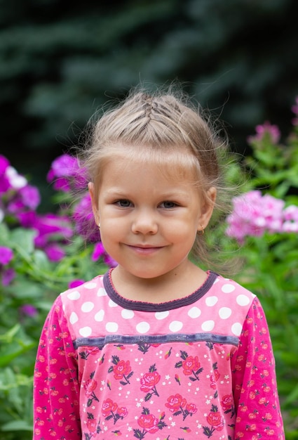 Portret van een verlegen Kaukasisch meisje van vier jaar oud die naar de camera kijkt in het zomerpark